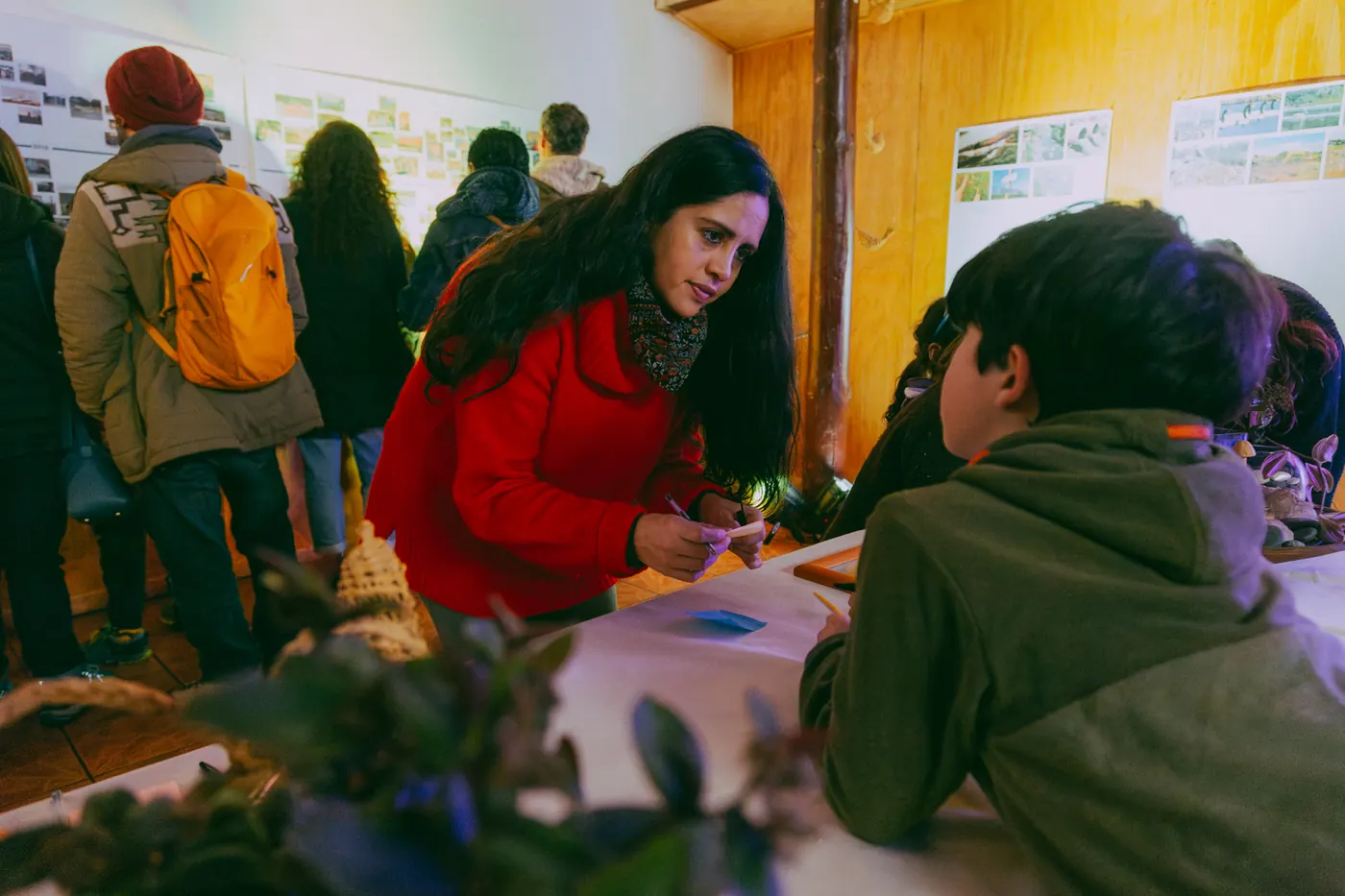 Mujer señalando un muro de fotografías del humedal en un encuentro comunitario.