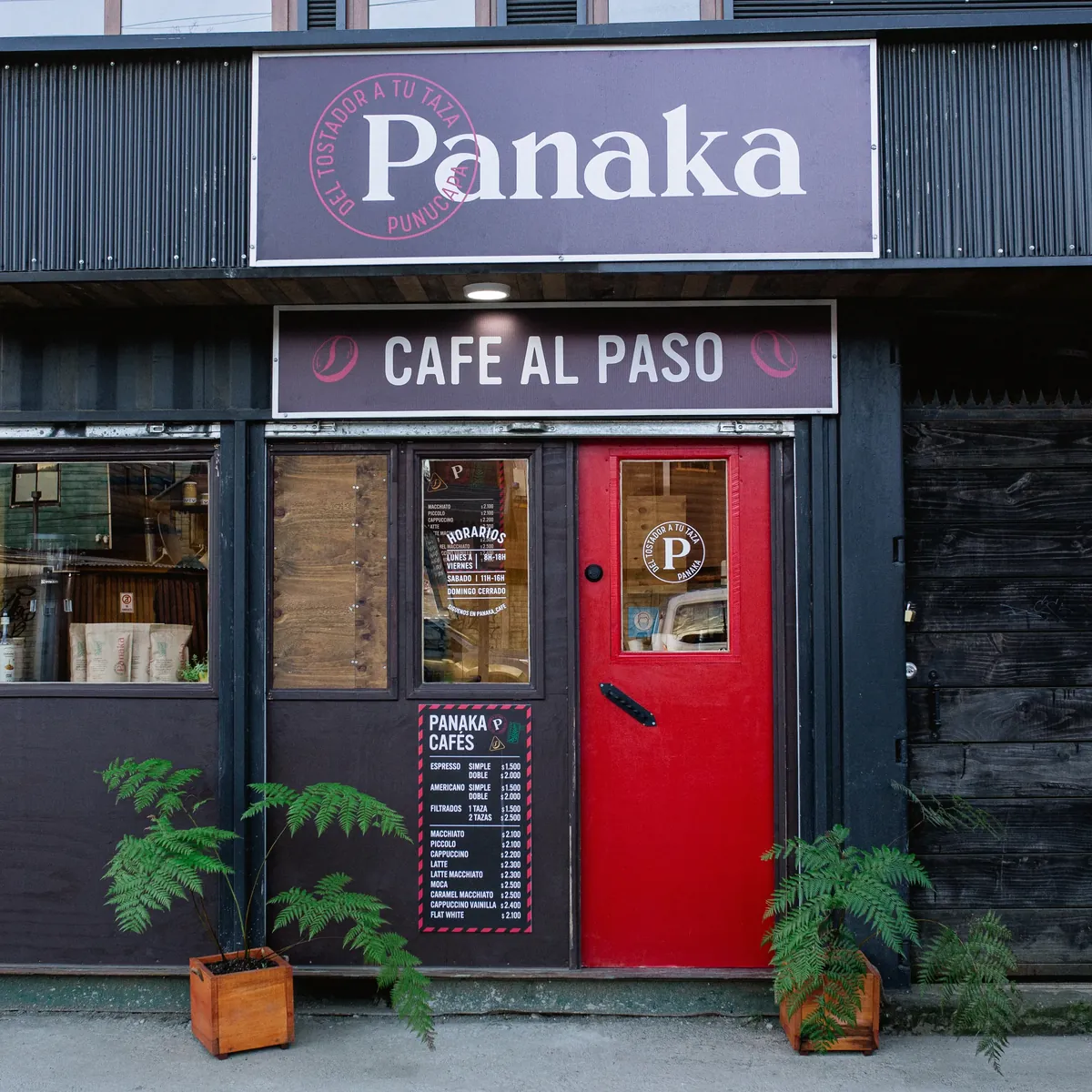 Fachada de madera oscura de Panaka, café al paso, con puerta roja.
